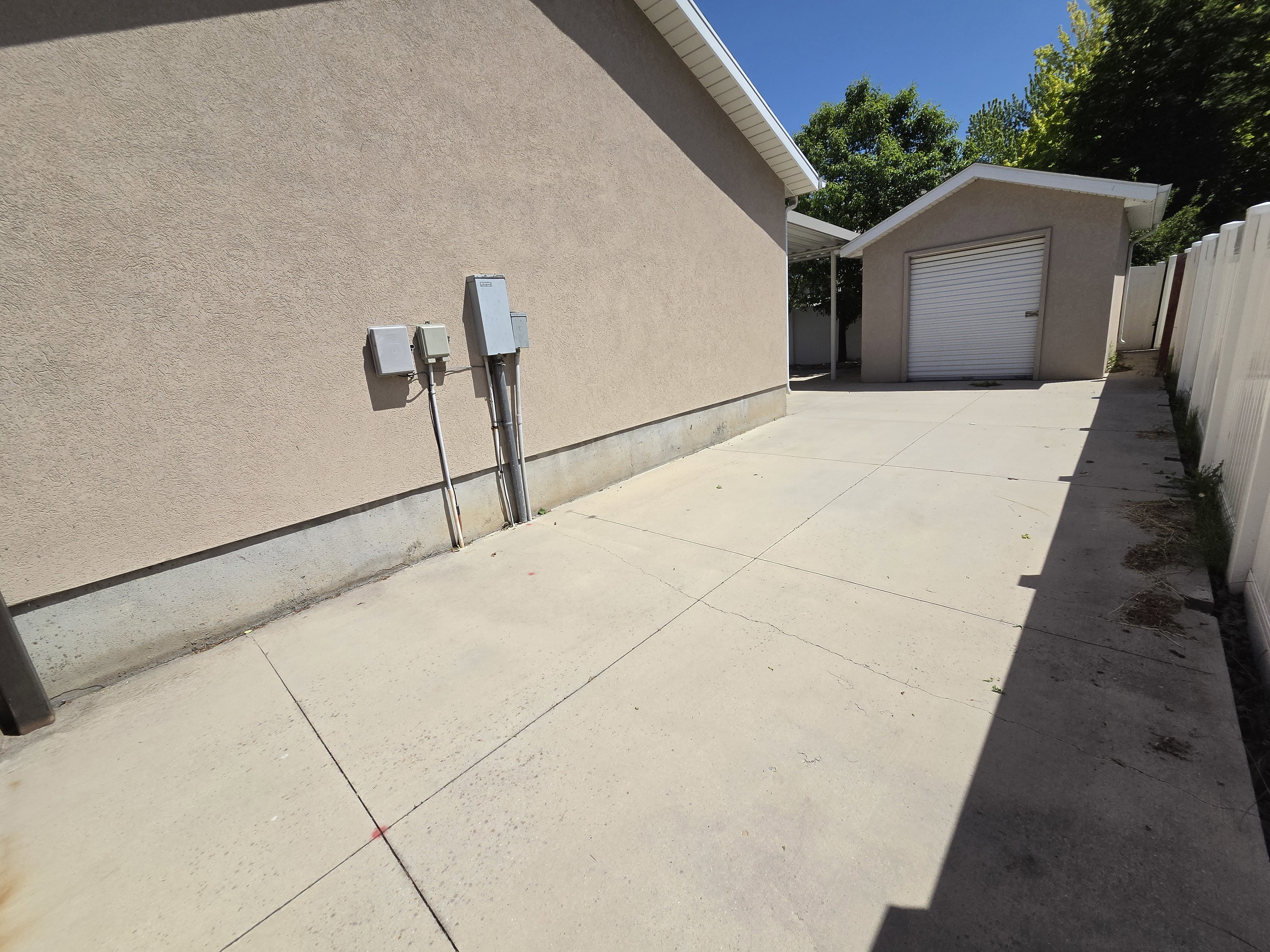 Expansive concrete driveway leading to a detached single-car garage with a roll-up door
