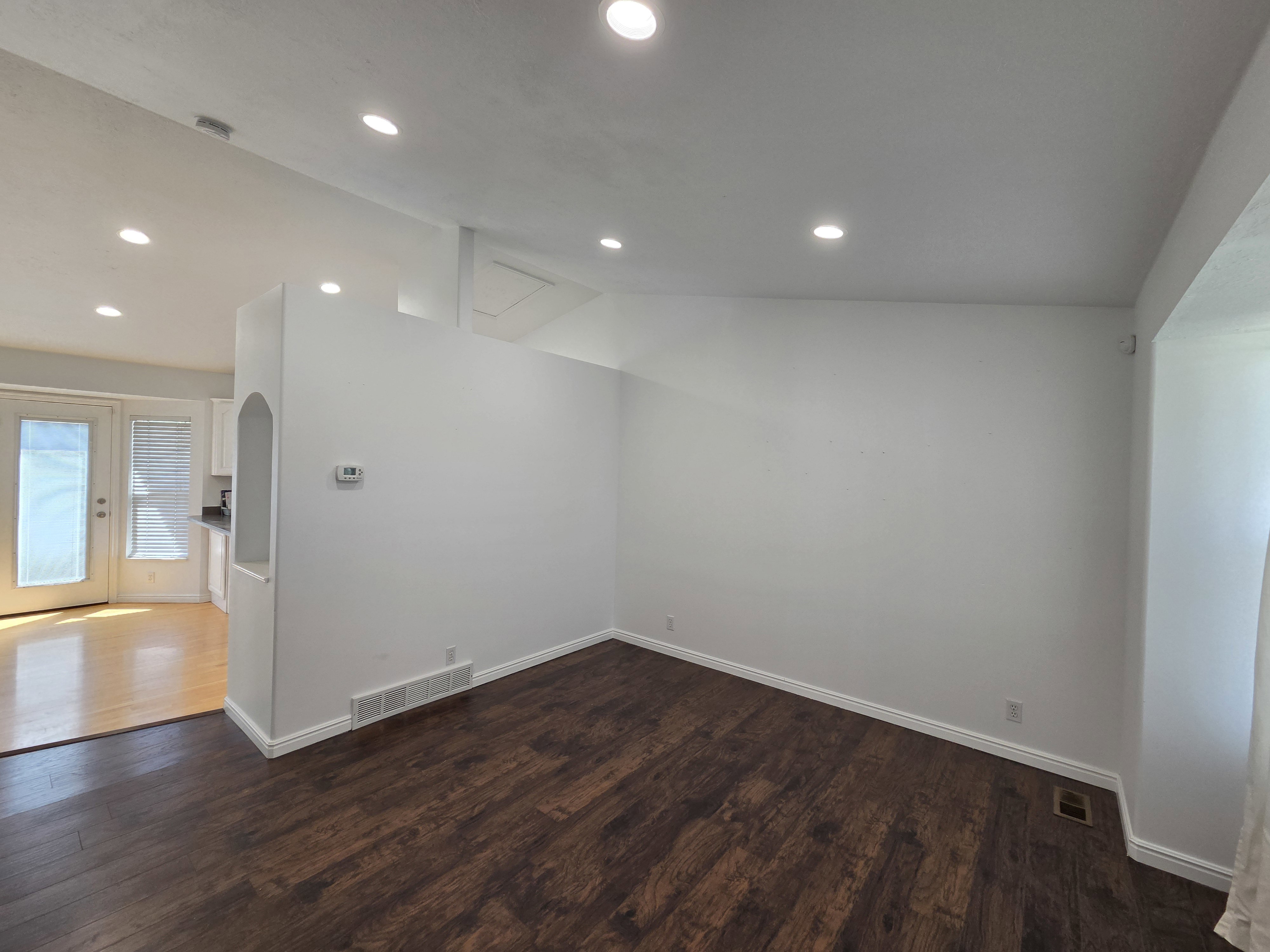 Spacious room featuring rich wood-finish flooring, recessed lighting, and white baseboards