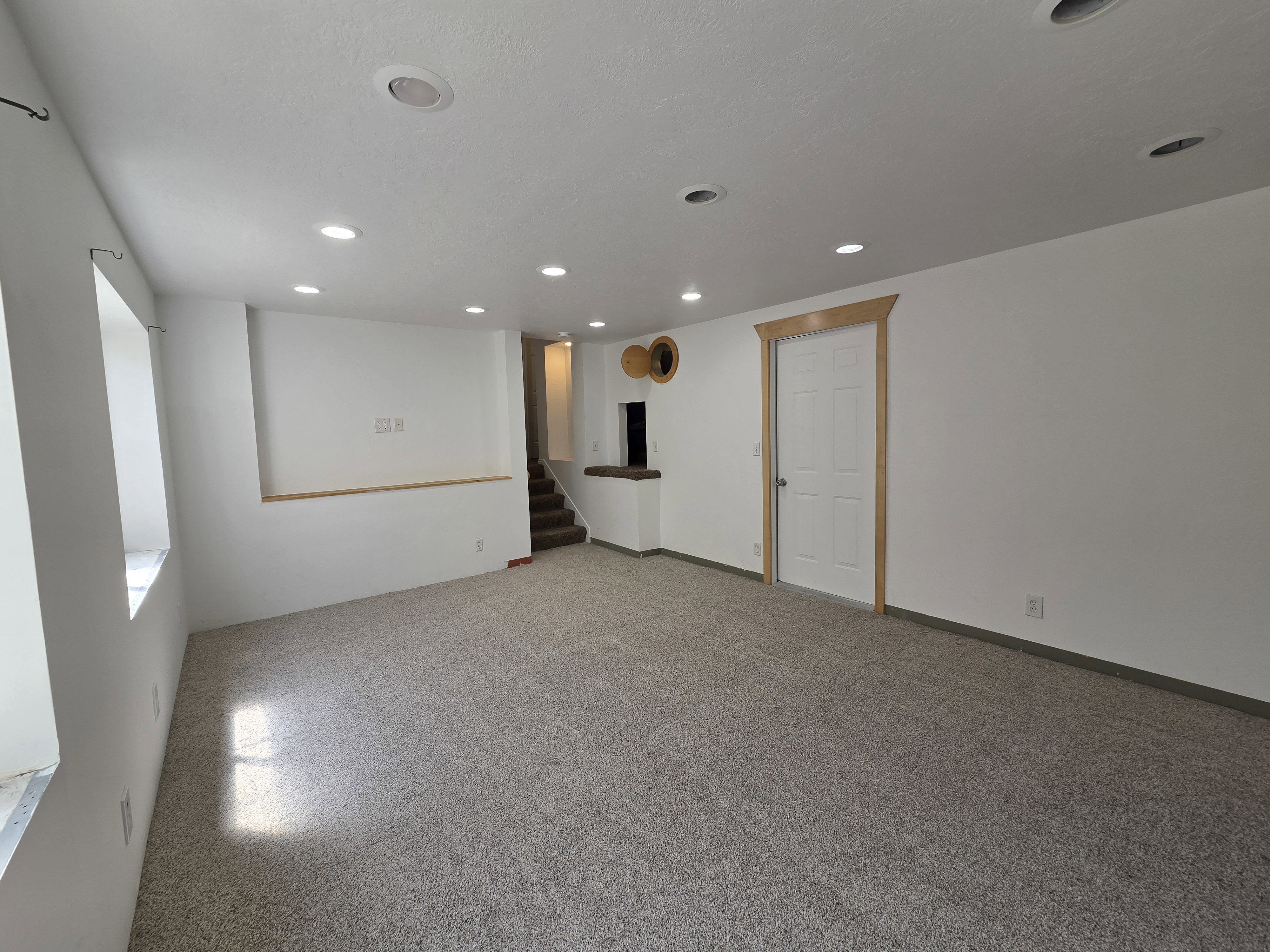 Spacious lower-level room featuring light gray carpeting and recessed lighting