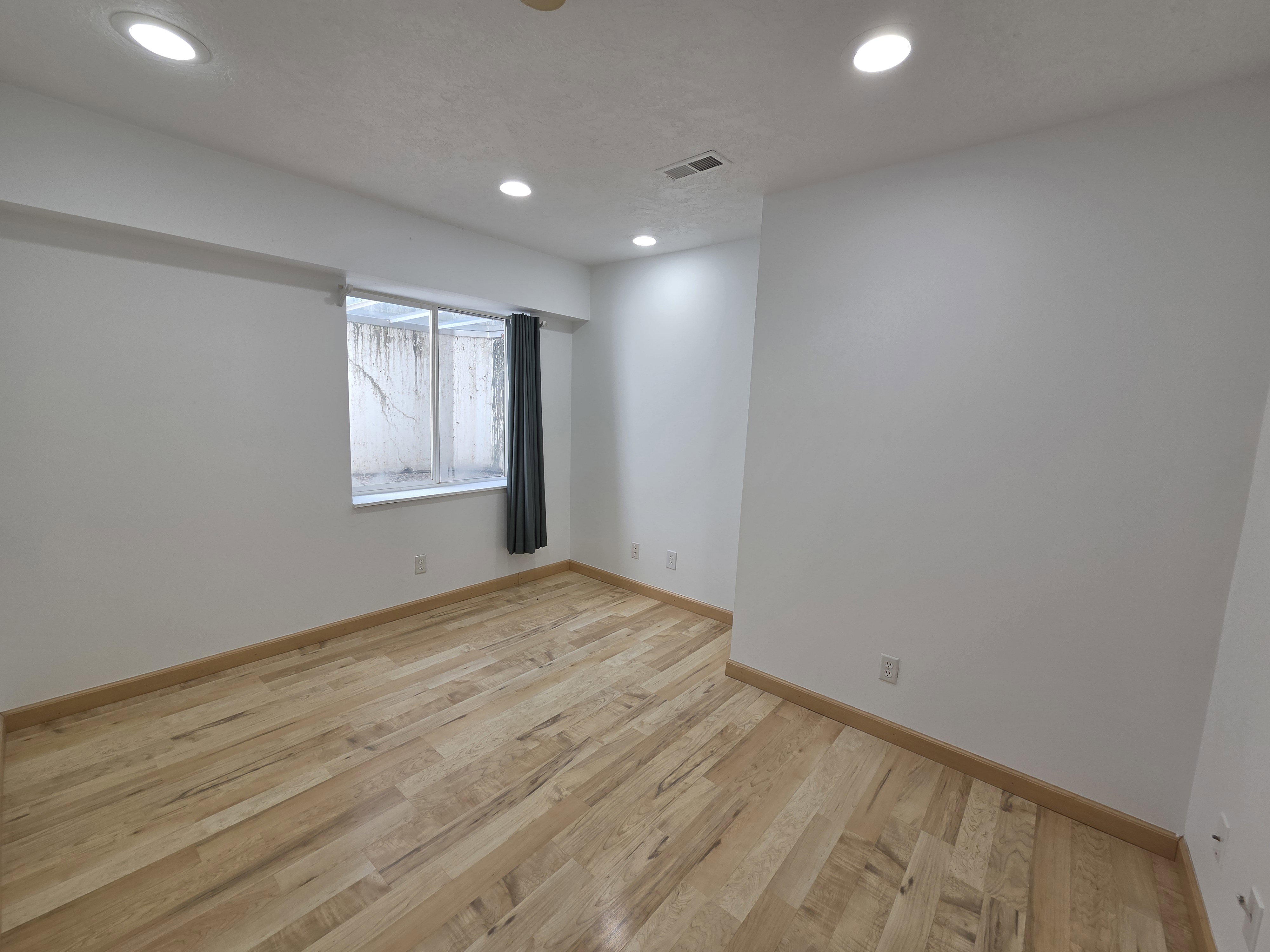 Room featuring wood-finish flooring, recessed ceiling lighting, and a window