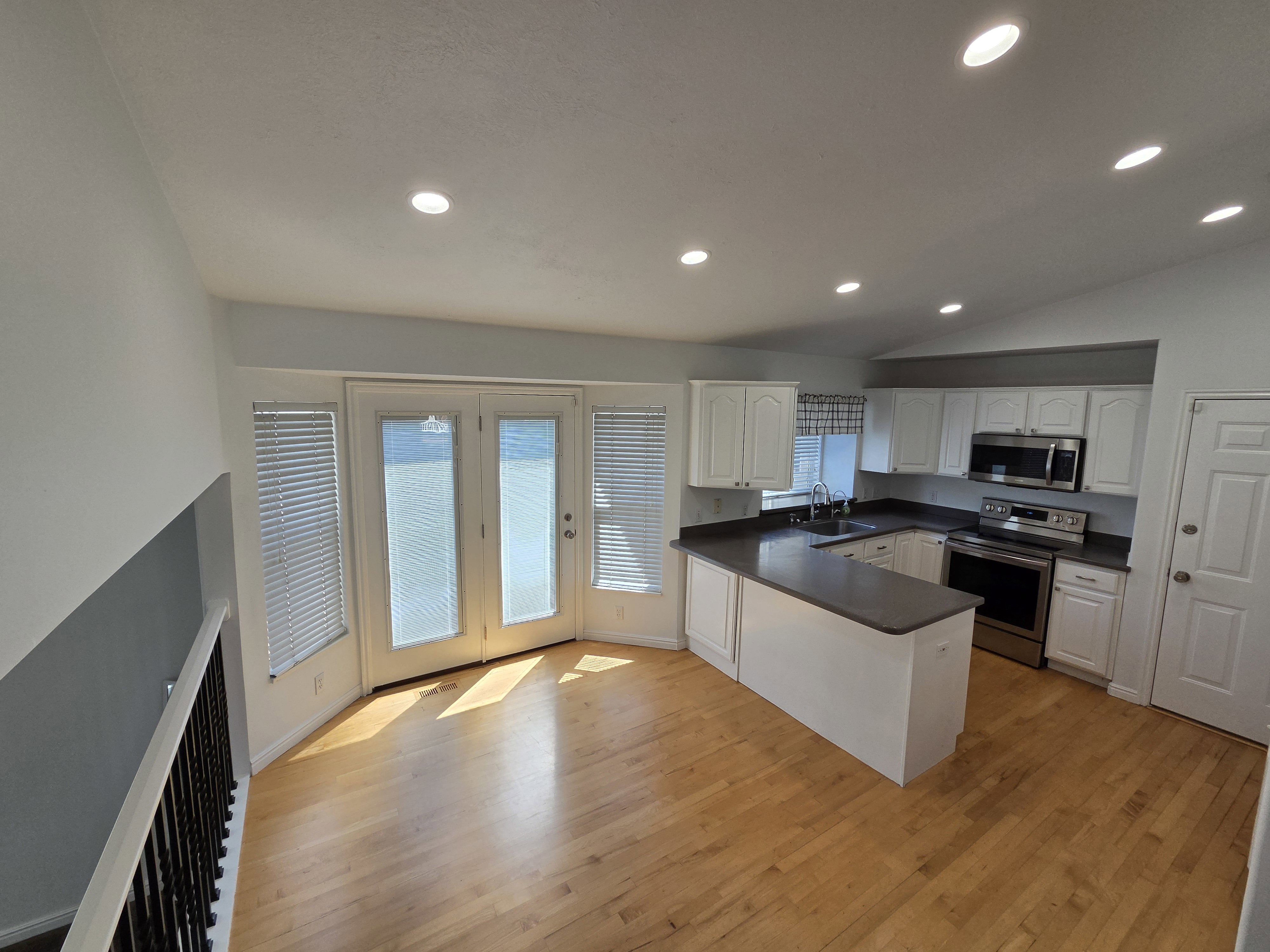Open-concept kitchen with recessed lighting, white cabinetry, dark countertops, and stainless steel appliances