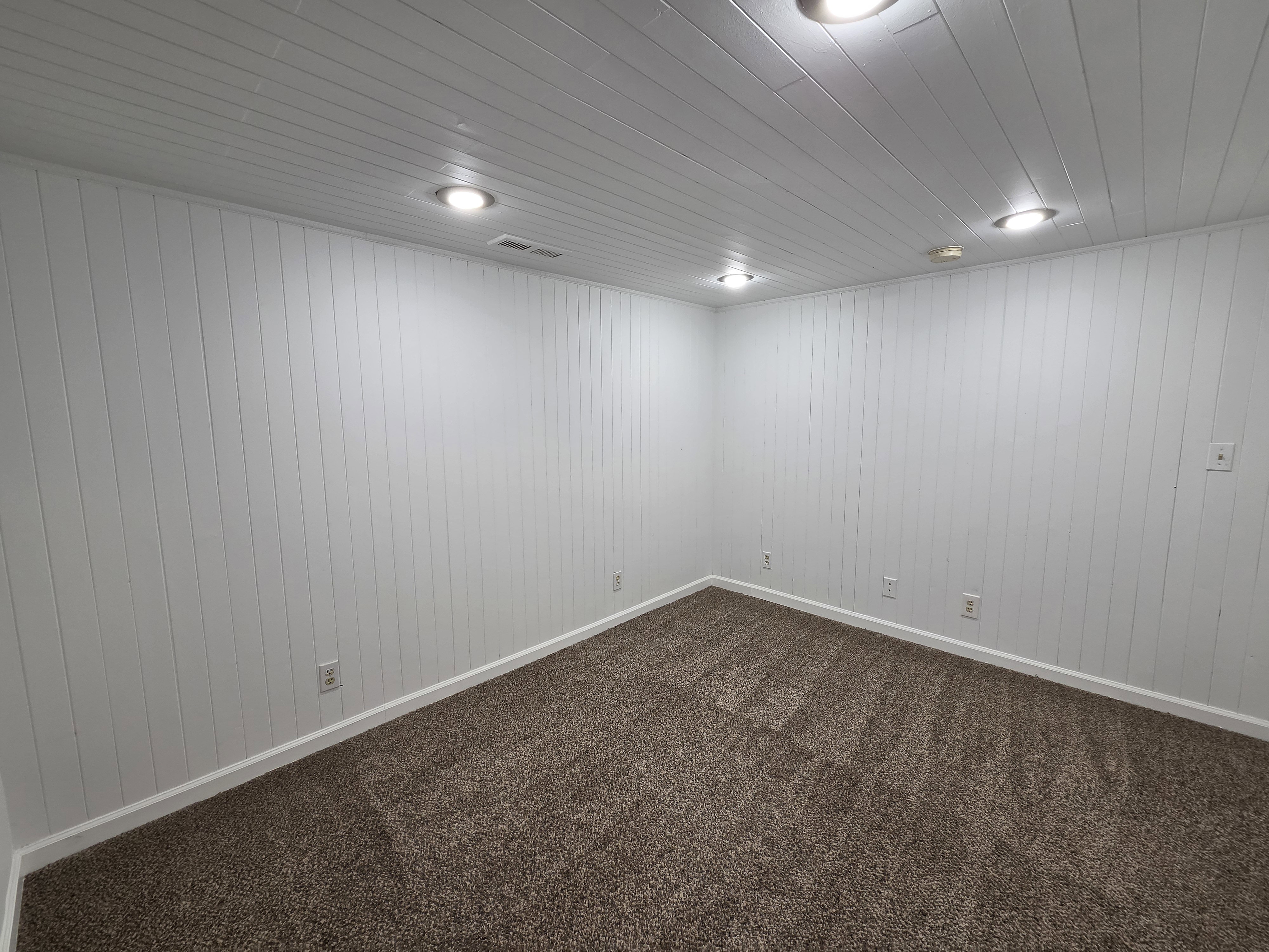 Room featuring shiplap walls, recessed lighting, and brown textured carpeting