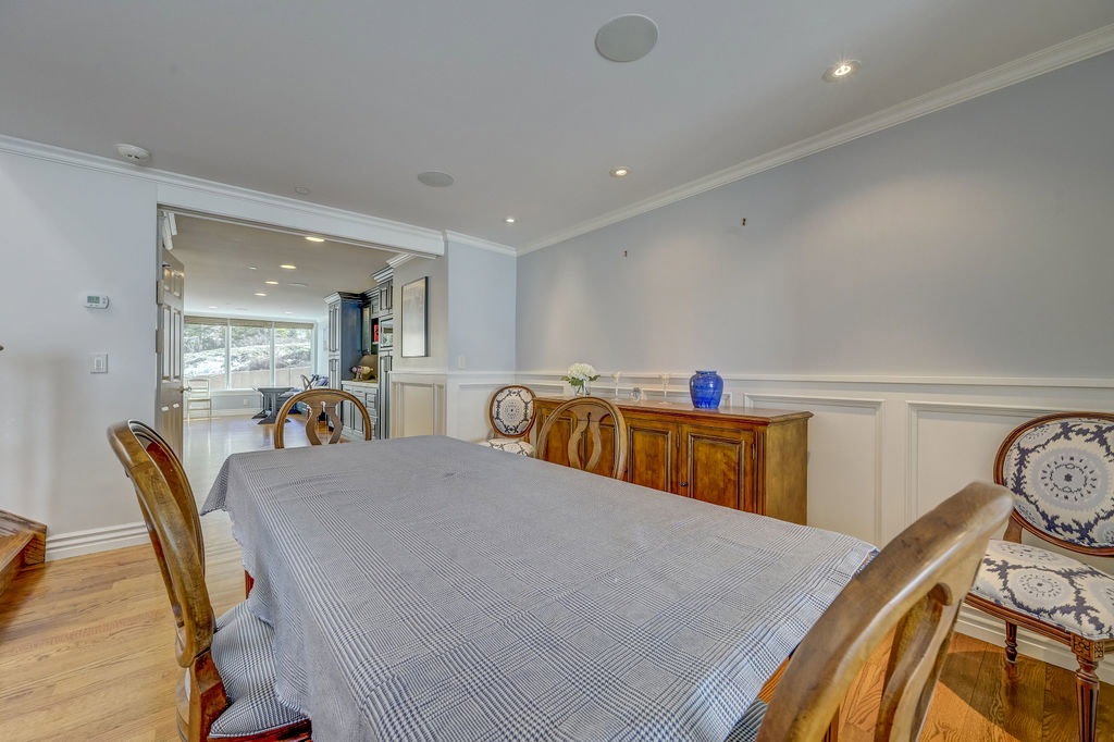 Dining area featuring wood-finish flooring, crown molding, recessed lighting, wainscoting, and an open entryway