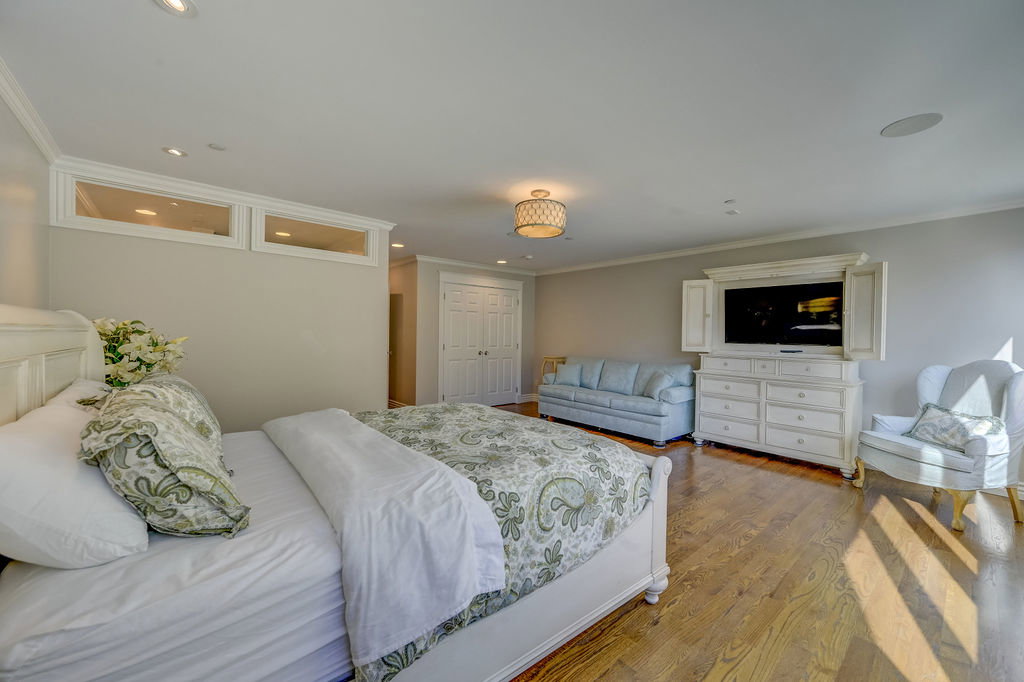 Spacious room featuring hardwood flooring, recessed lighting, crown molding, and a built-in speaker system