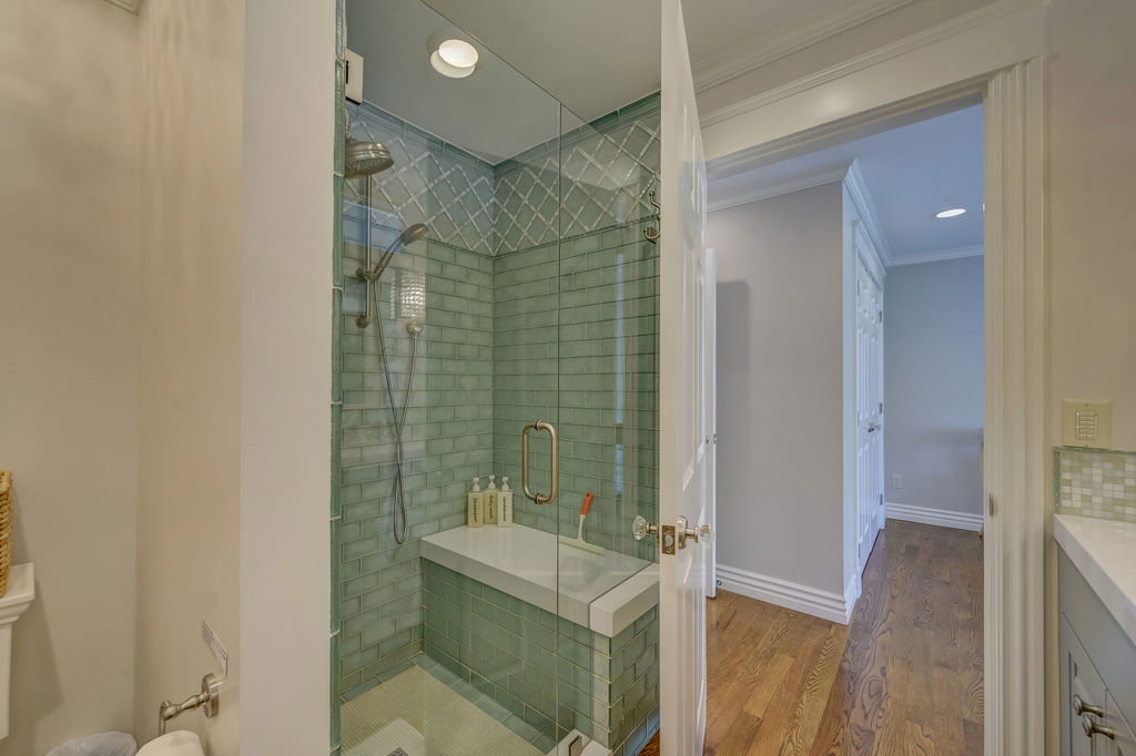 Glass-enclosed shower featuring subway tile with decorative mosaic accents and an integrated bench