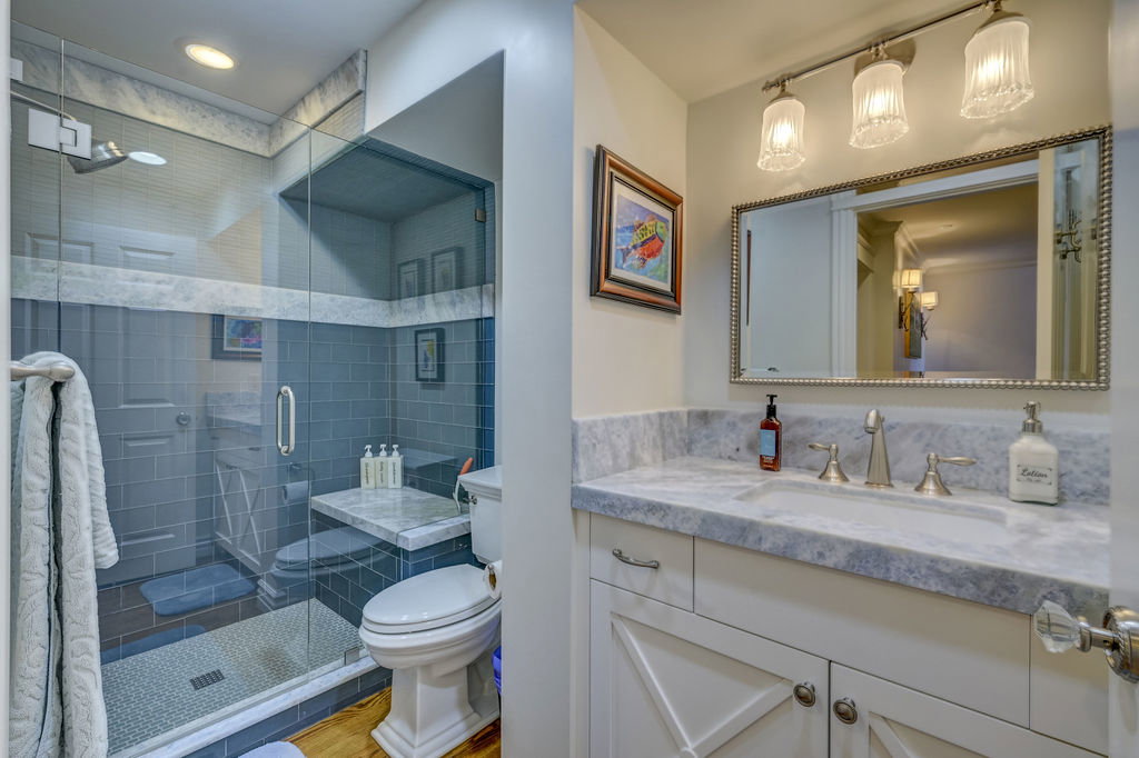 Bathroom featuring a glass-enclosed shower with subway tile, a vanity with a stone countertop, a rectangular undermount sink, and brushed nickel fixtures