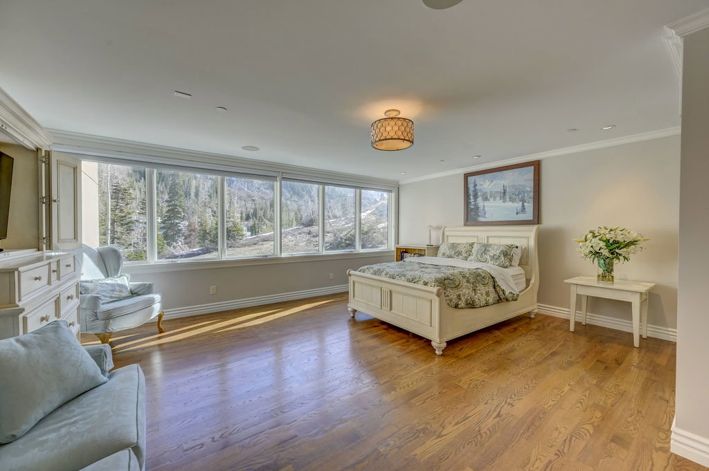 Expansive room featuring a wall of windows, hardwood flooring, recessed lighting, crown molding, and a decorative ceiling fixture