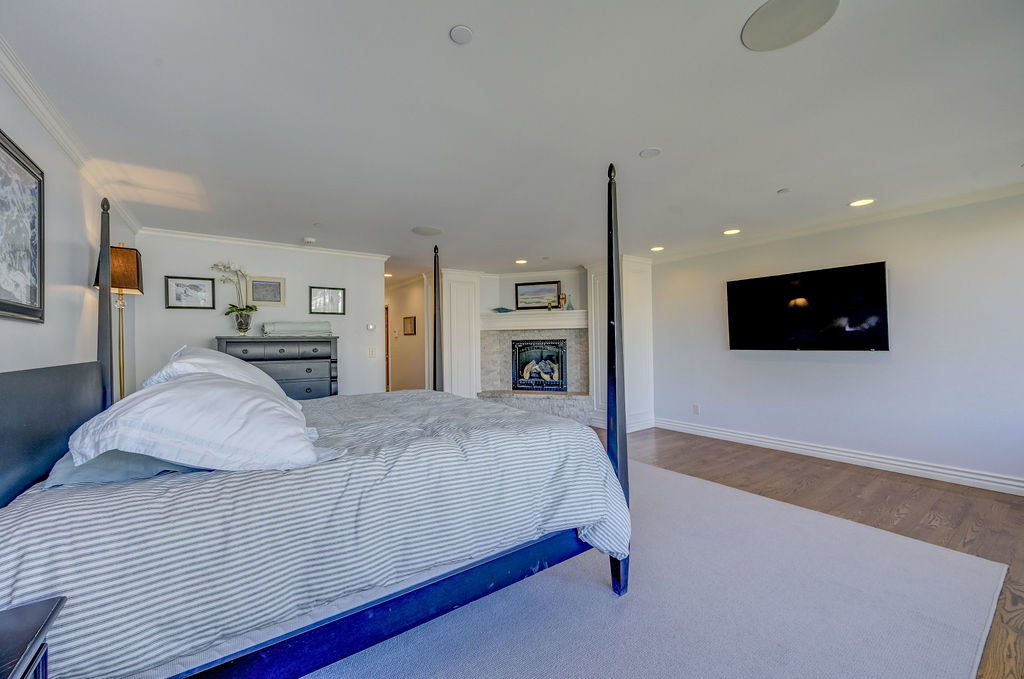 Spacious bedroom featuring recessed lighting, a built-in fireplace with a stone surround, and crown molding
