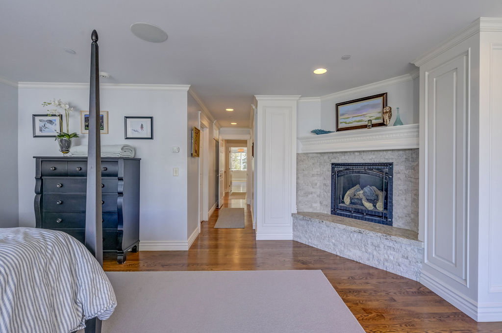 Bedroom featuring a corner fireplace with a stone surround and hearth, hardwood flooring, recessed lighting, and crown molding