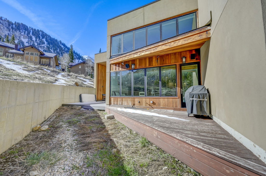 Exterior featuring a multi-level deck, wood siding accents, large windows, and an upper-level window bank
