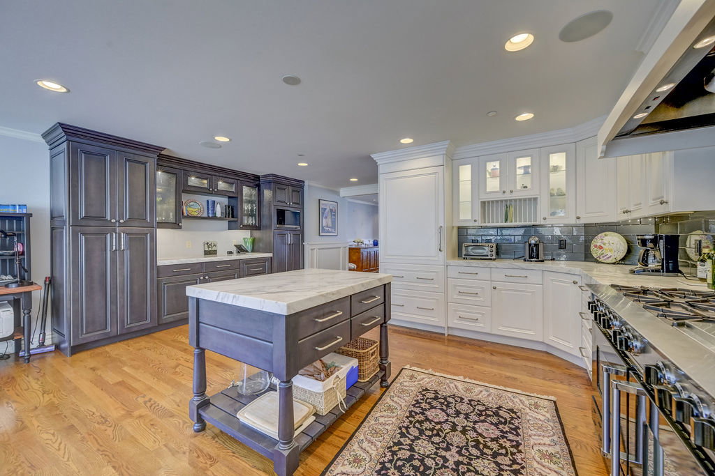 Gourmet kitchen featuring a wood-finish floor, a large center island with a stone countertop, recessed lighting, and a professional-grade gas range