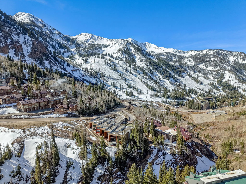 Mountain property featuring a collection of structures, snow-covered slopes, and evergreen trees