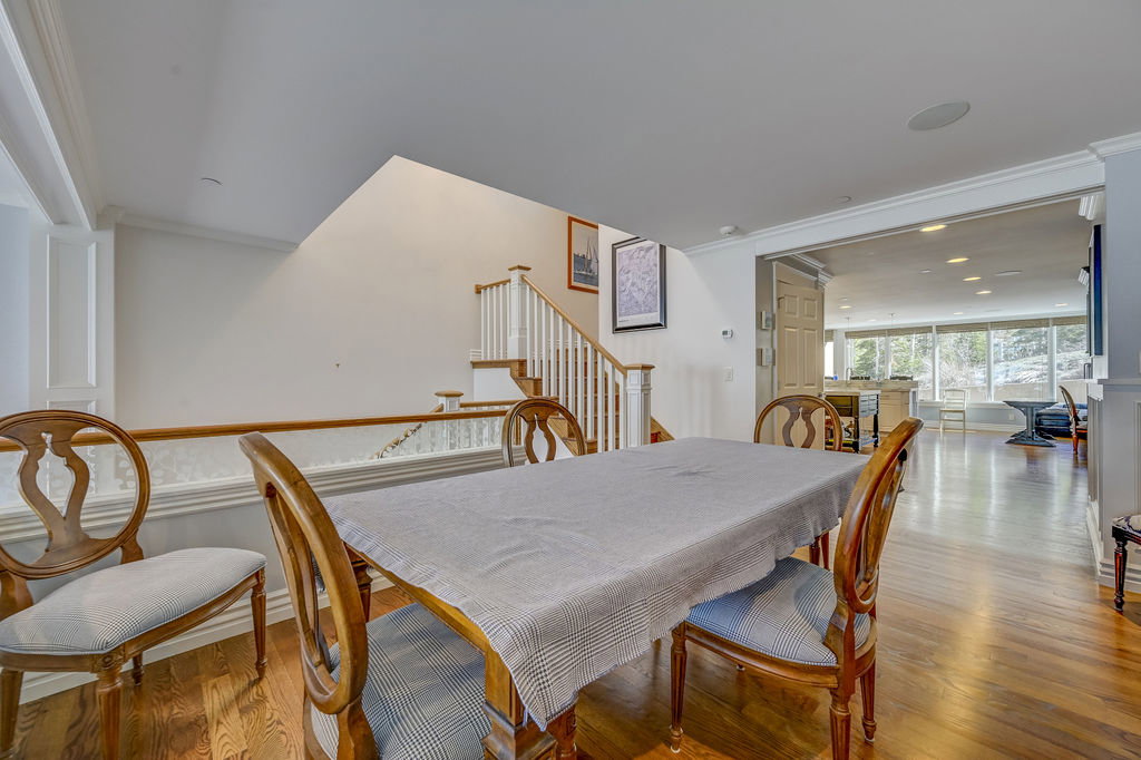 Open-concept dining area featuring wood-finish flooring, white trim details, and a staircase with white balusters