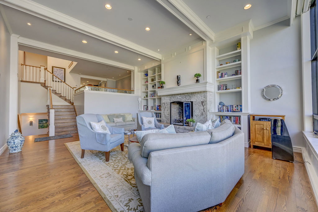 Spacious living area featuring wood-finish flooring, recessed lighting, and a stone-clad fireplace with mantel