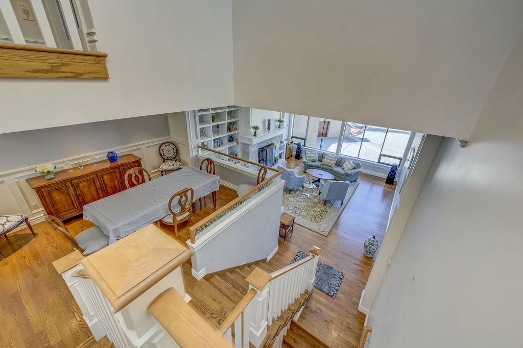 Hardwood flooring visible throughout, including the grand staircase with white balusters and wood handrails