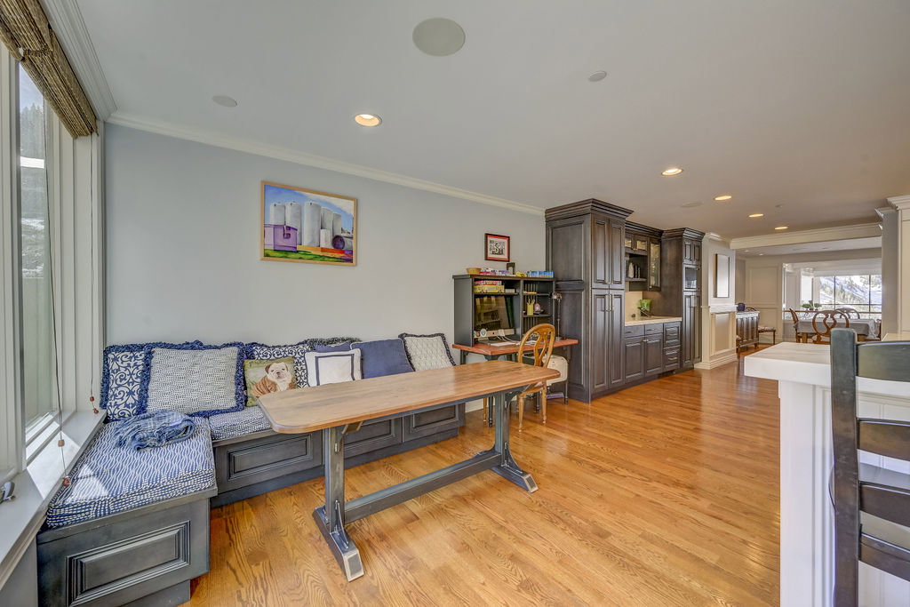 Open-concept living area featuring a built-in window seat, wood-finish flooring, recessed lighting, and dark wood cabinetry with a light-toned countertop