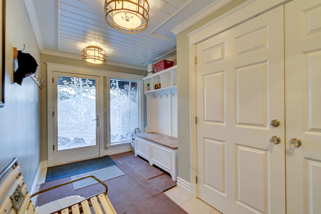 Entryway featuring a white paneled door with etched glass, a wood-finish bench, and built-in storage with coat hooks