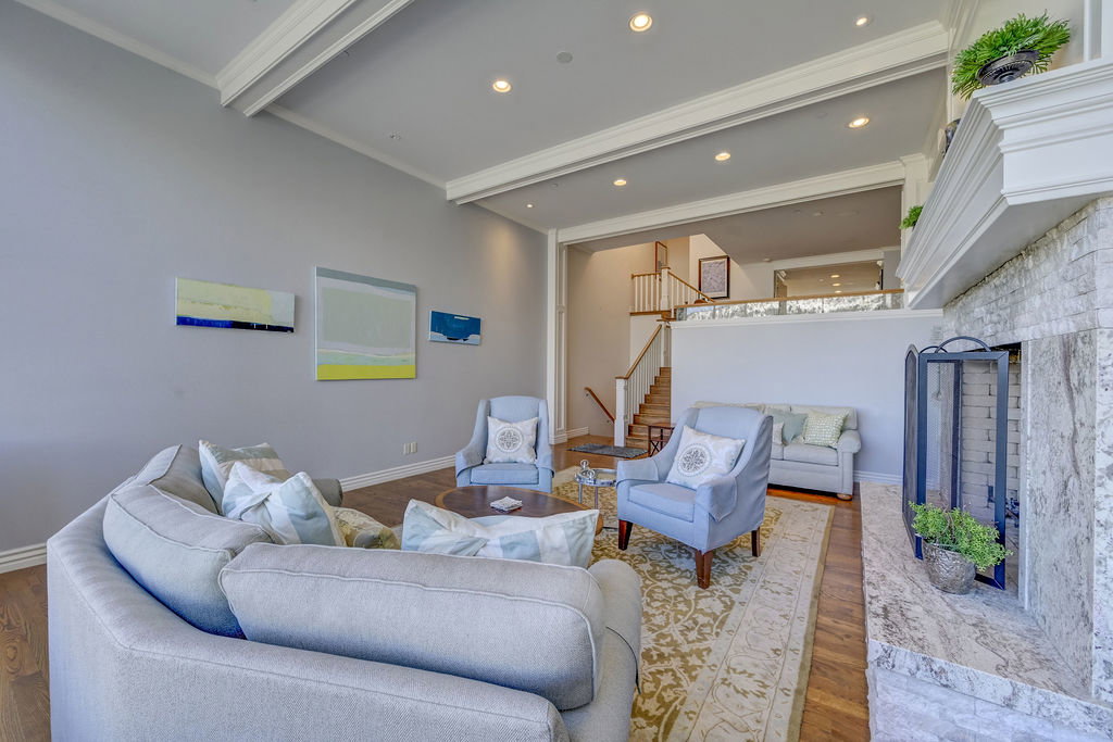 Spacious living area featuring high ceilings with exposed beams, recessed lighting, and wood-finish flooring