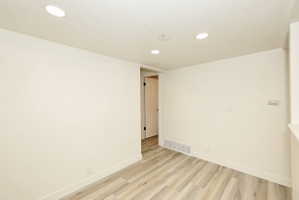 Spacious room featuring wood-finish flooring and recessed ceiling lighting