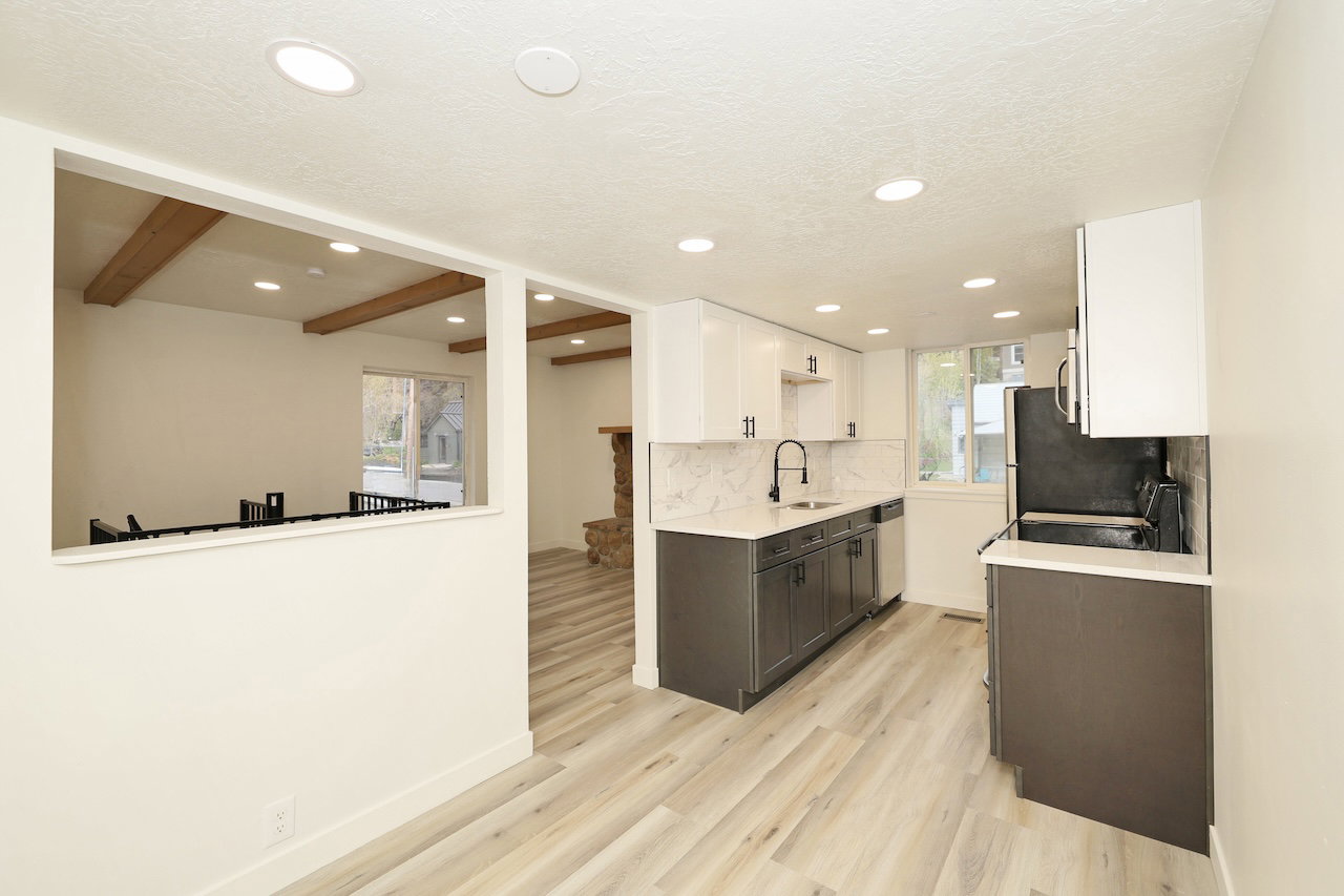 Modern kitchen featuring two-tone cabinetry, light wood-finish flooring, recessed lighting, a white quartz countertop, and a full tile backsplash