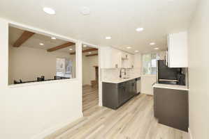Modern kitchen featuring two-tone cabinetry, light wood-finish flooring, recessed lighting, a white quartz countertop, and a full tile backsplash