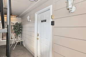 Entryway with horizontal siding and a paneled door featuring a brass handle