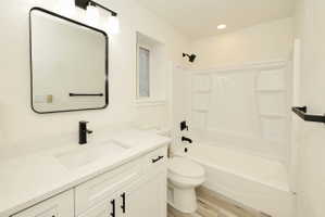 Bathroom featuring a white vanity with integrated sink, quartz-finish countertop, and matte black hardware
