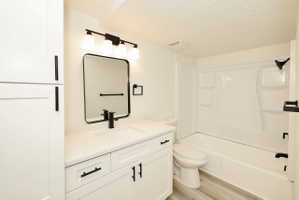 Contemporary bathroom featuring a white vanity with a light-colored countertop, a rectangular black-framed mirror, and a modern black faucet