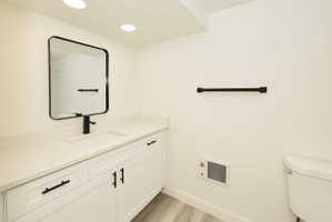 Bathroom vanity featuring a light-toned countertop with an integrated sink, white cabinetry with matte black hardware, and a framed rectangular mirror
