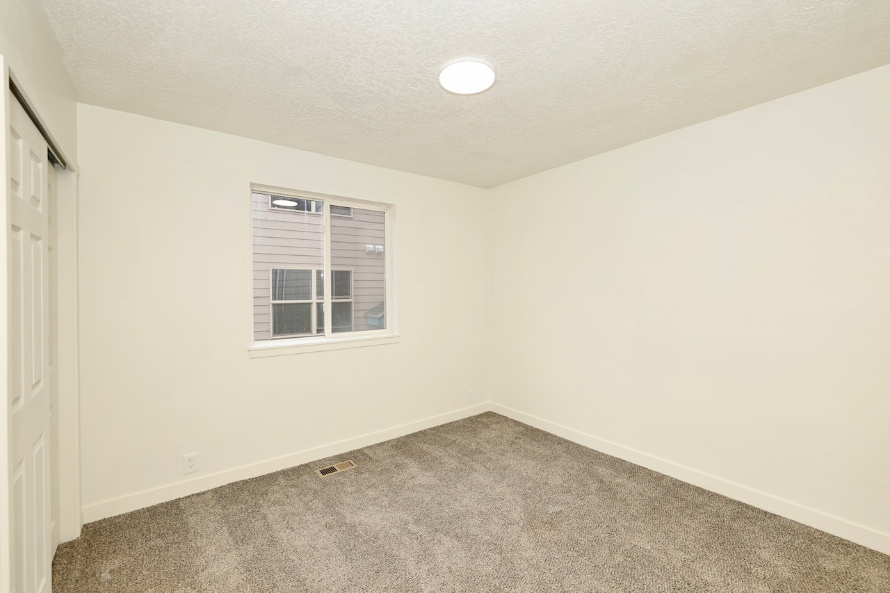 Carpeted room with a single window, a white trim baseboard, and a flush-mount ceiling light fixture