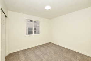 Carpeted room with a single window, a white trim baseboard, and a flush-mount ceiling light fixture