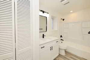 Bathroom featuring a white vanity with an integrated sink, quartz-finish countertop, and matte black fixtures