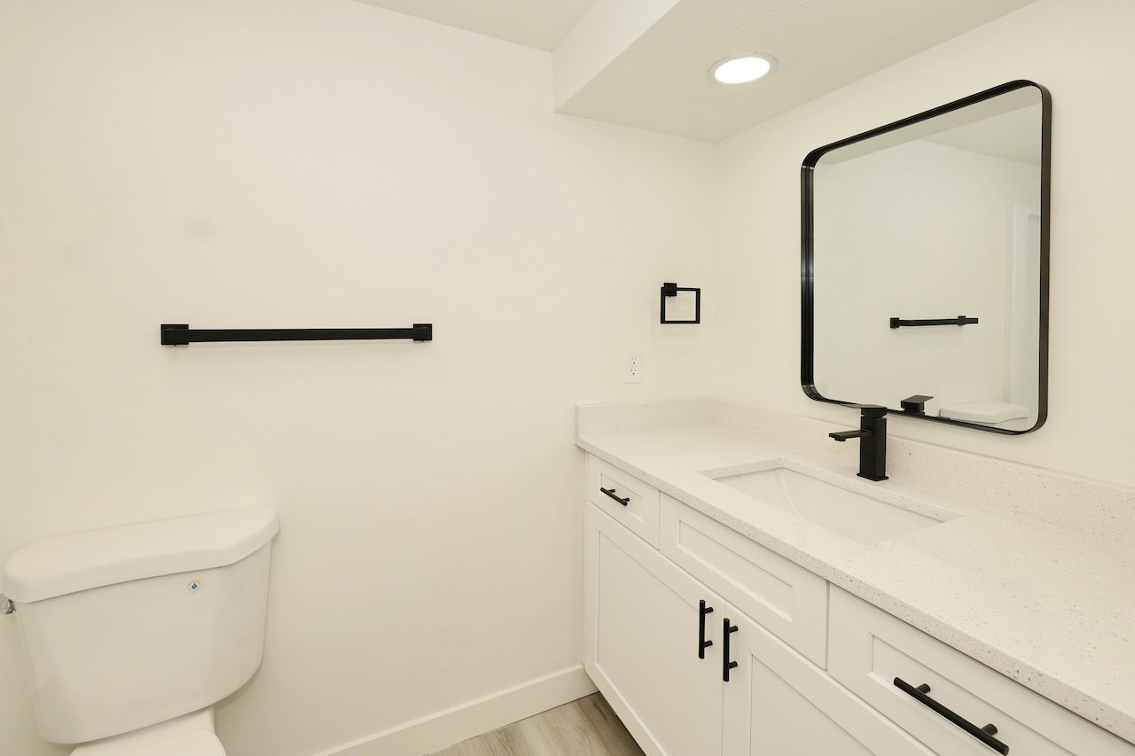 Bathroom featuring a contemporary vanity with white shaker-style cabinetry, a built-in rectangular sink, and a light-toned countertop