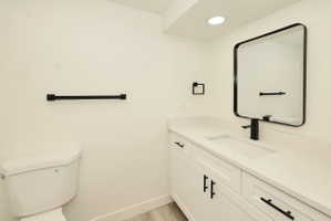 Bathroom featuring a contemporary vanity with white shaker-style cabinetry, a built-in rectangular sink, and a light-toned countertop