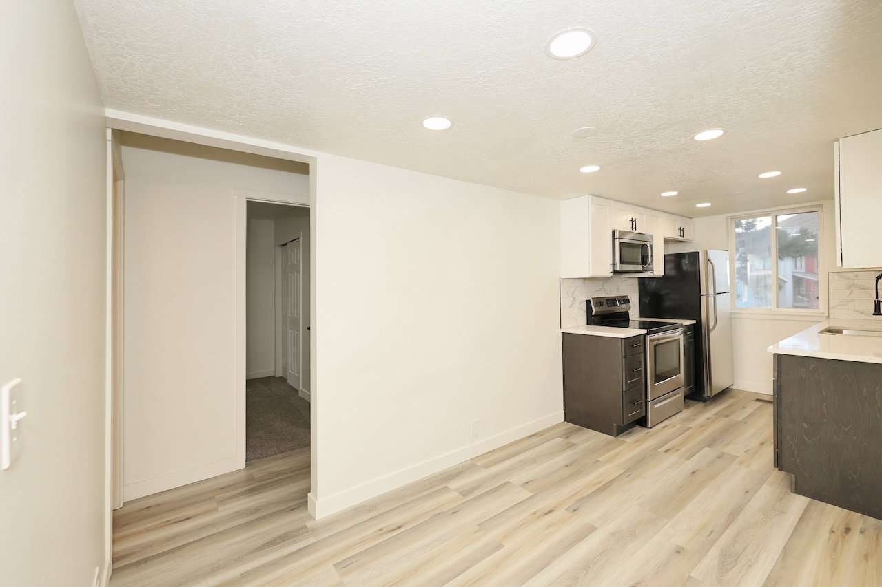 Contemporary kitchen featuring stainless steel appliances, light wood-finish flooring, recessed lighting, white upper cabinetry, and dark lower cabinetry