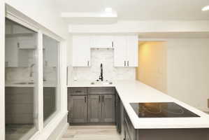 Modern kitchen featuring two-tone cabinetry with matte black hardware, white countertops, and a white subway tile backsplash