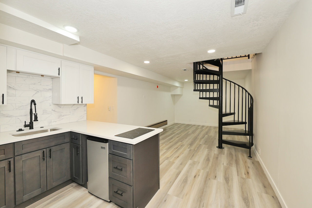 Open-concept living space with a contemporary kitchen area and spiral staircase