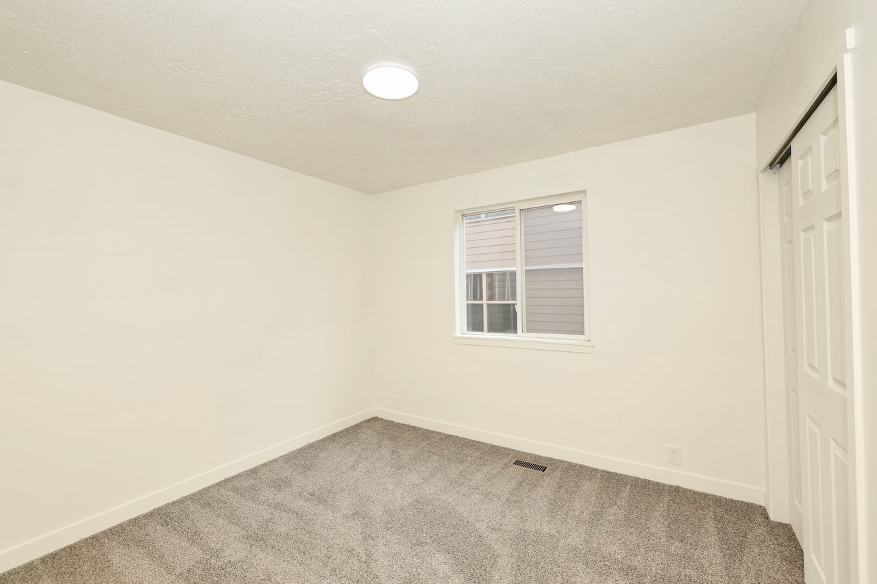Bright interior space featuring a window with blinds, neutral wall paint, and gray carpet flooring