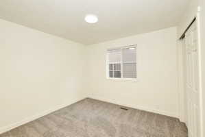 Bright interior space featuring a window with blinds, neutral wall paint, and gray carpet flooring