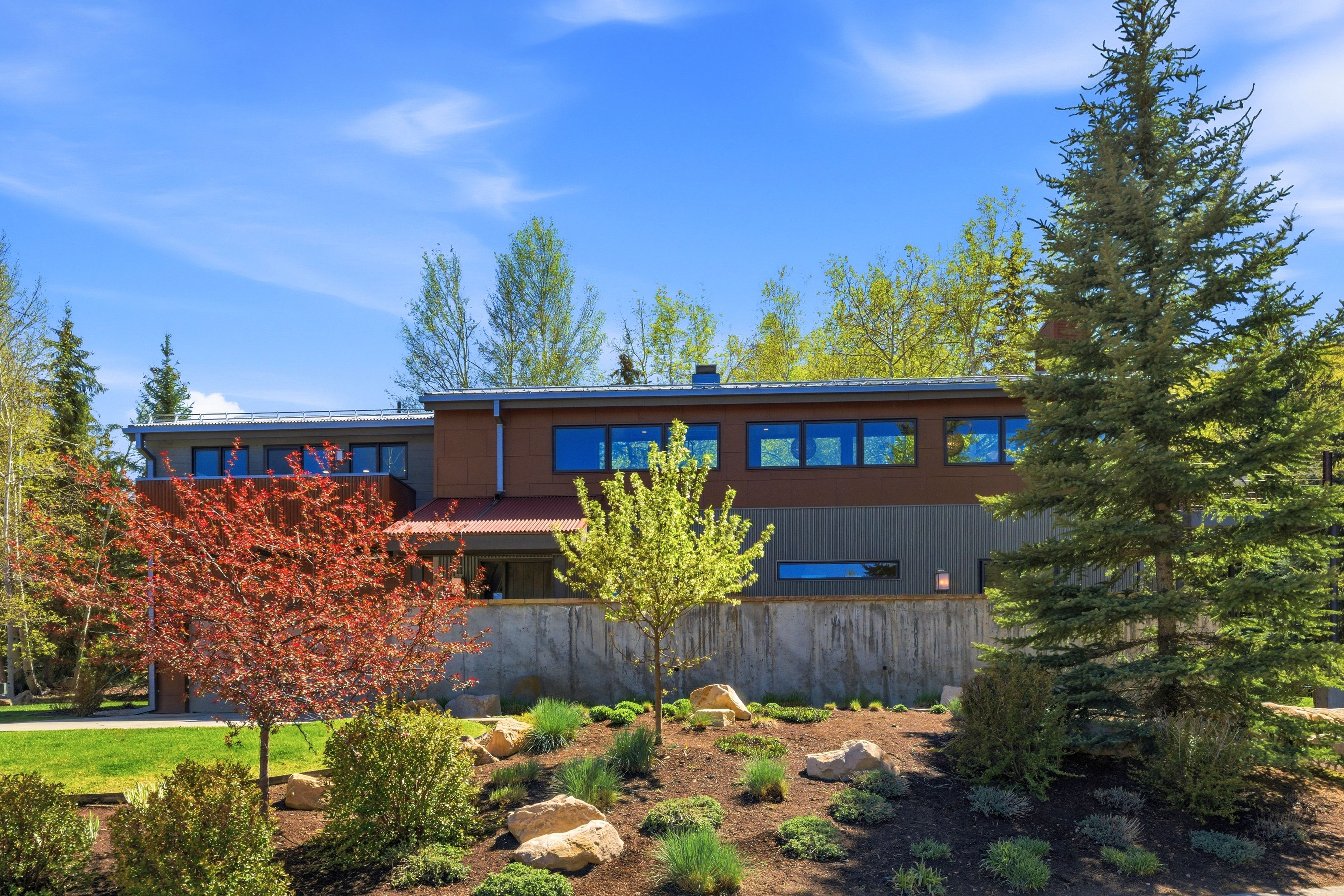 Modern architectural structure featuring multi-level design, a concrete retaining wall, and horizontal siding