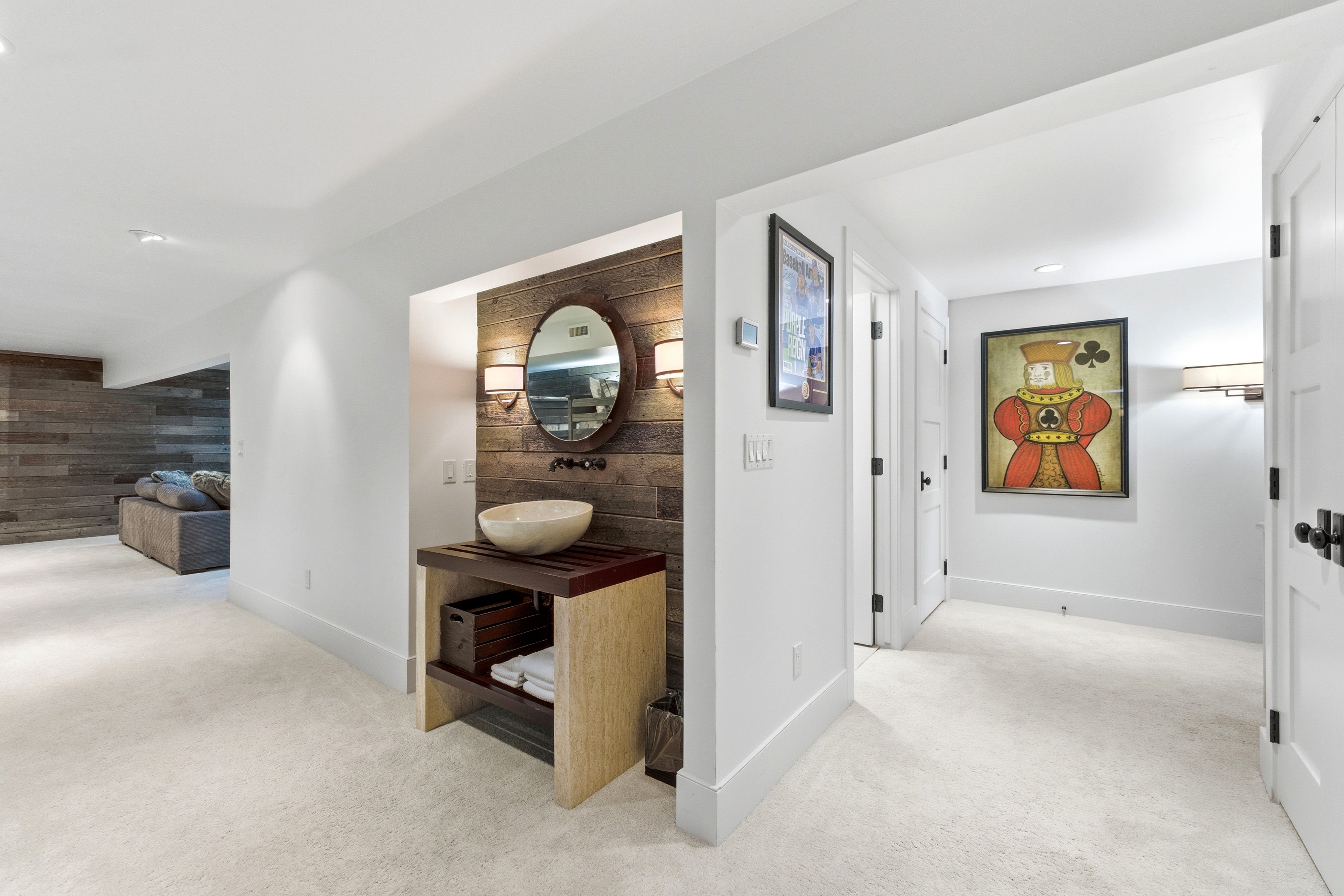 Powder room featuring a rustic wood-plank accent wall, vessel sink, and round mirror with two sconces