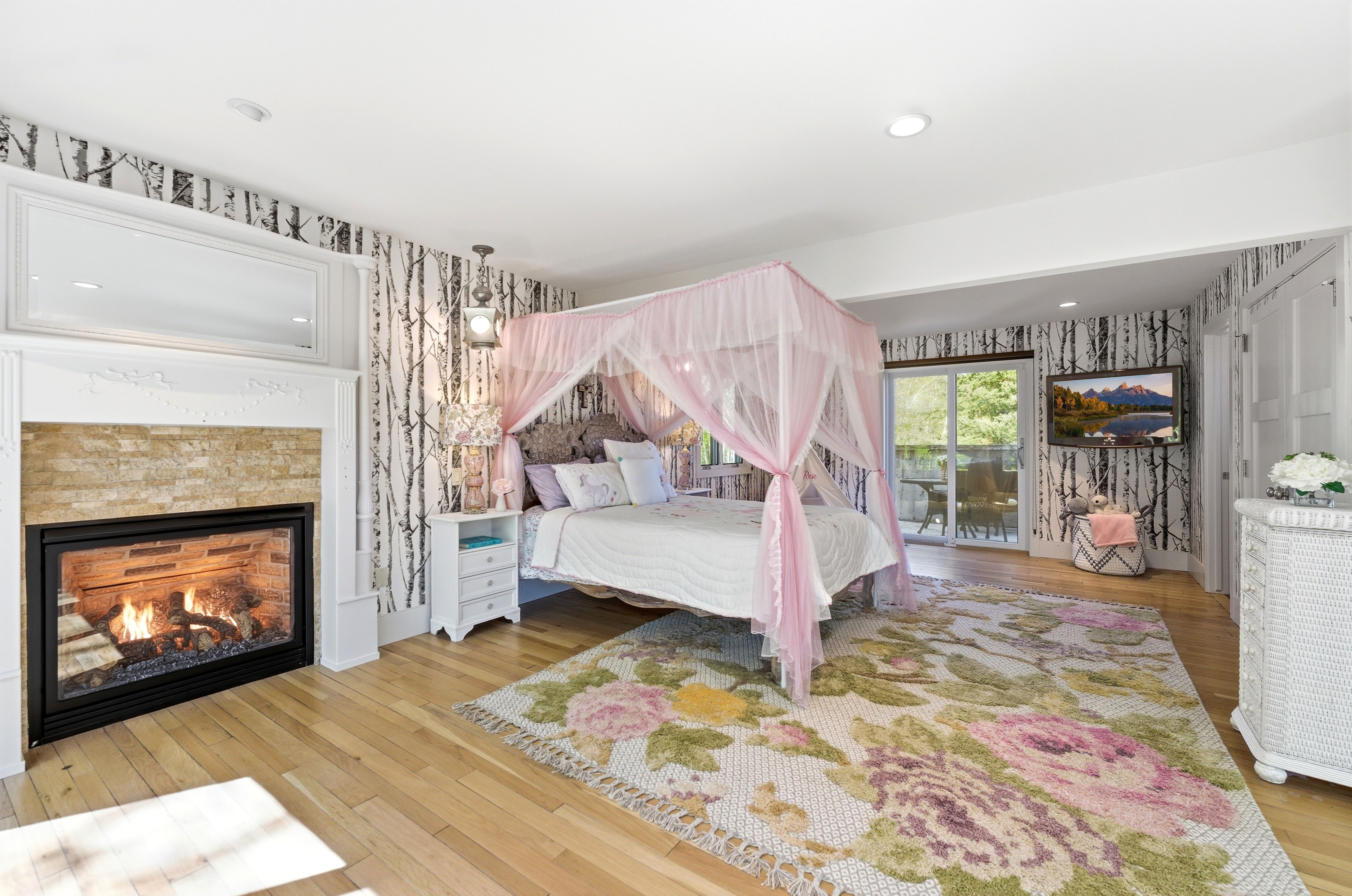 Hardwood flooring paired with a stone-clad fireplace and white mantel