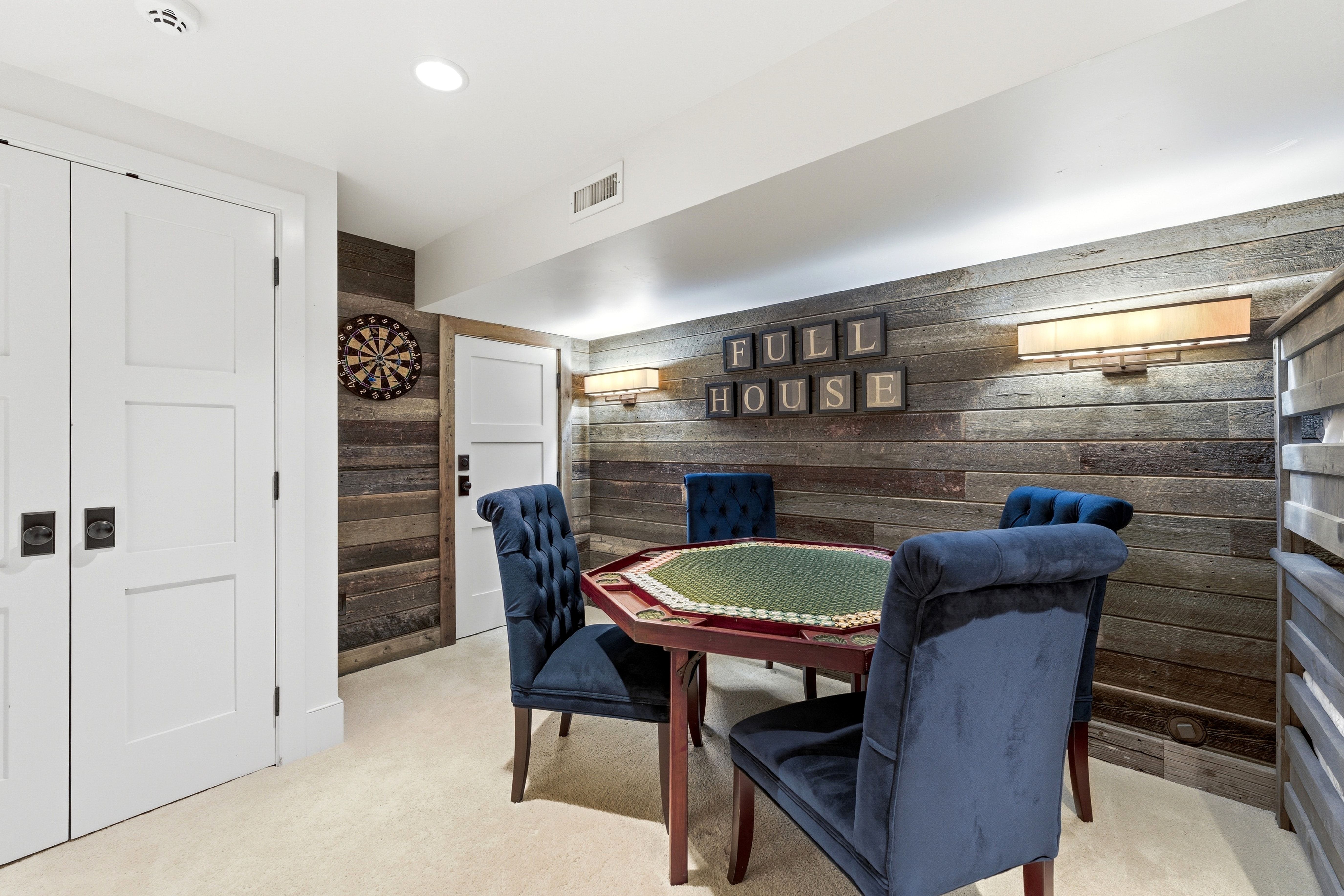 Reclaimed wood accent wall featuring sconce lighting, recessed ceiling lights, and light-colored carpeting