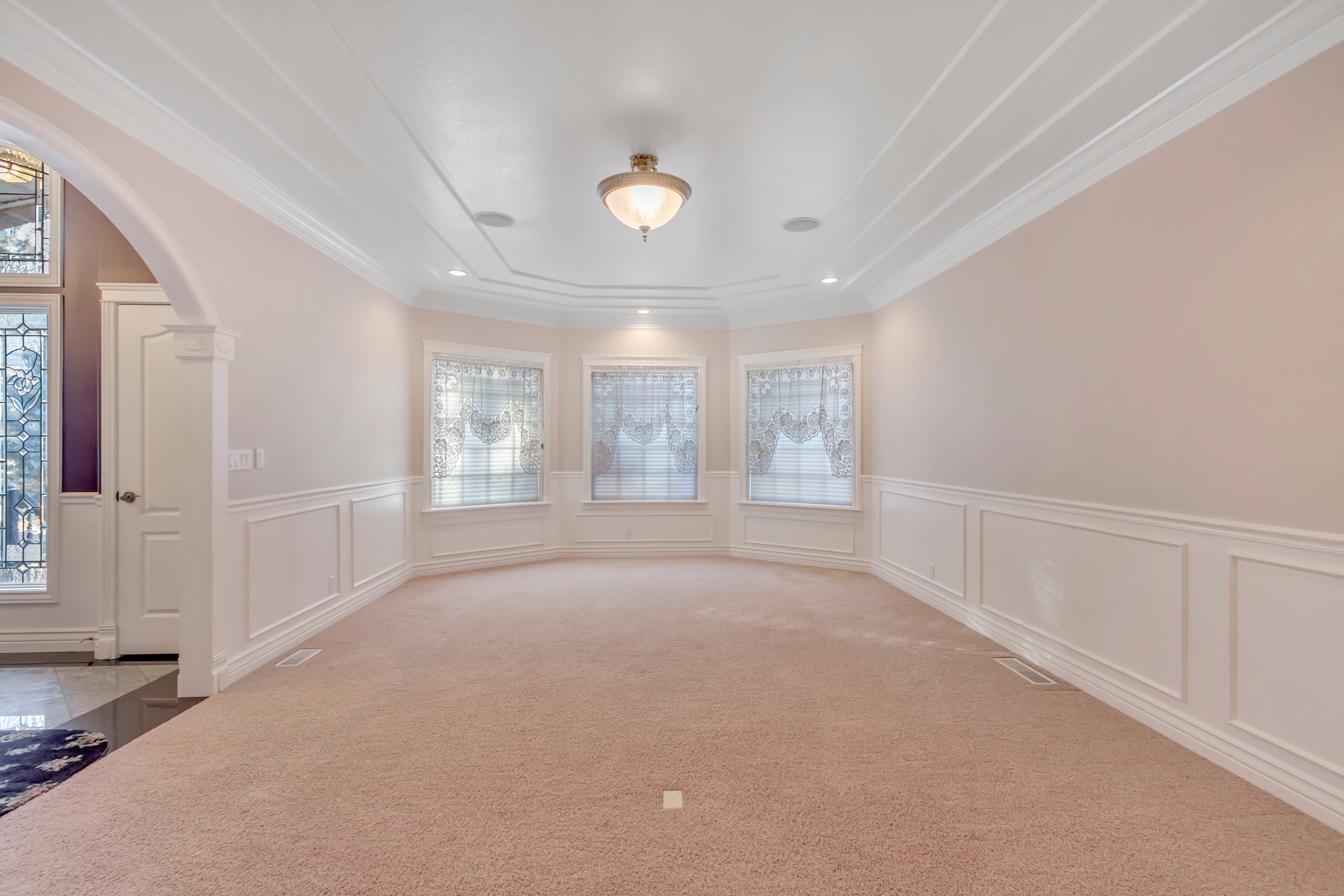 Expansive room featuring a tray ceiling with recessed lighting and a central flush mount fixture