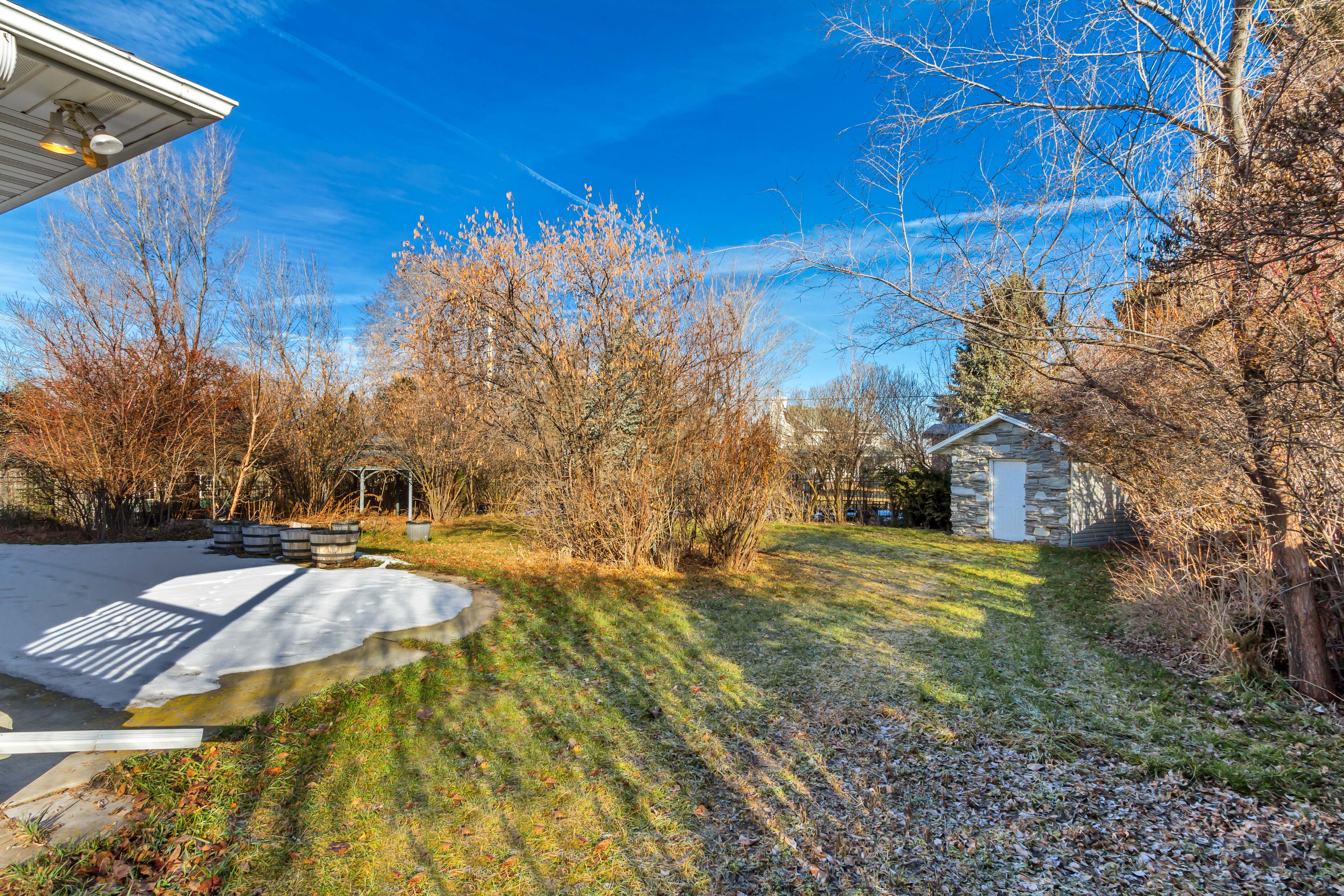 Expansive yard featuring a stone-clad shed, a gazebo, and mature landscaping