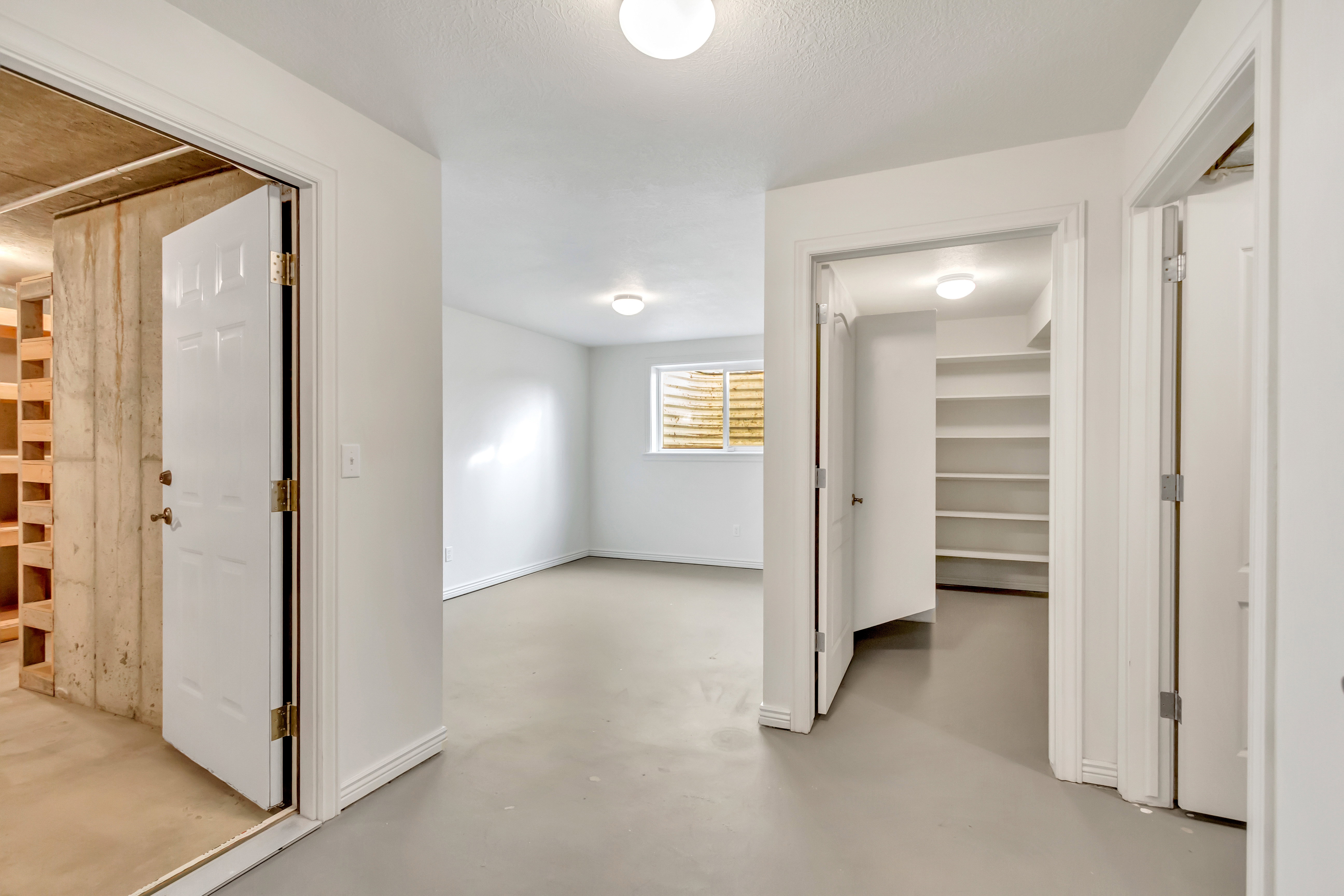 Open finished room with a window, light-toned flooring, and white walls