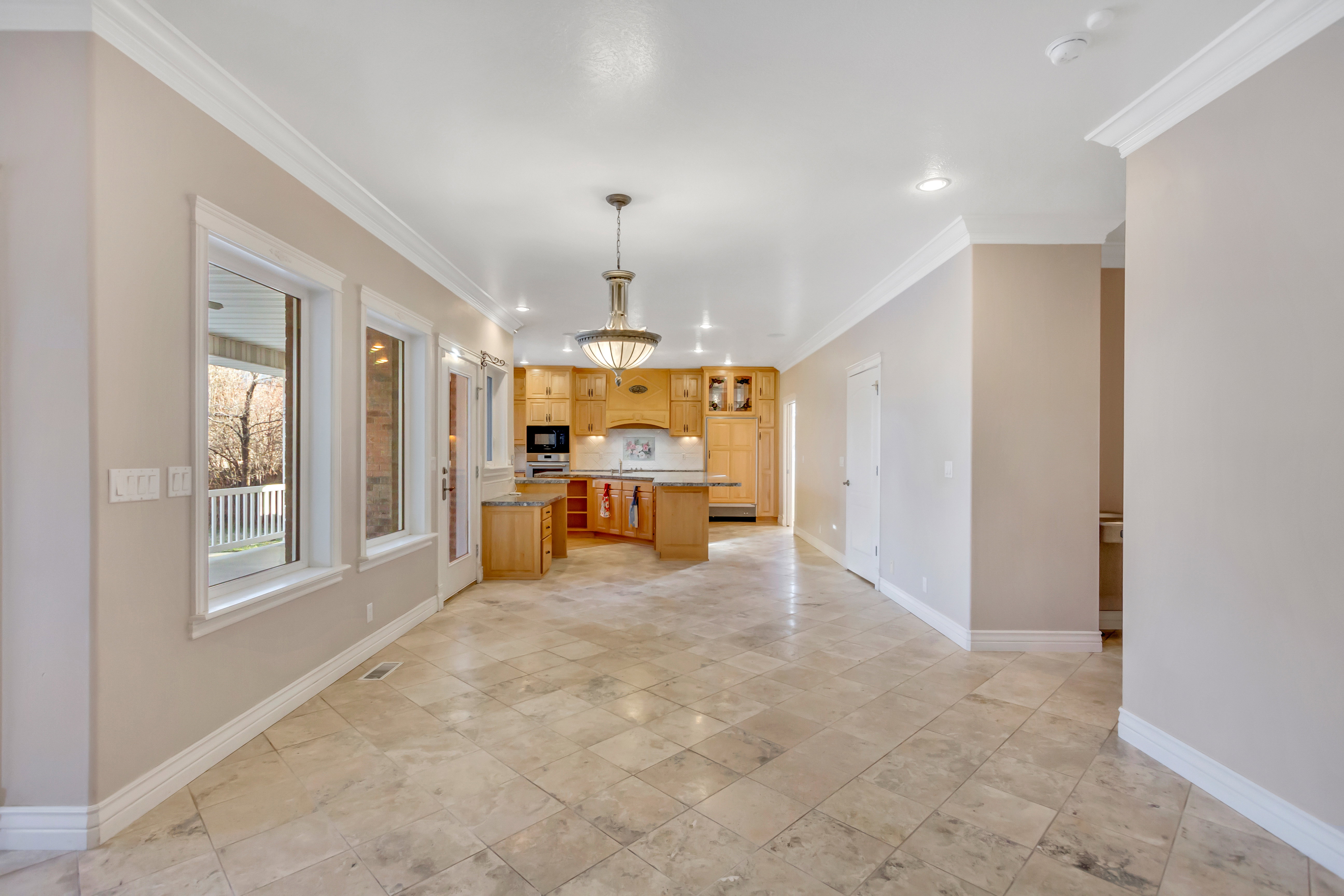 Spacious room featuring large format tile flooring, crown molding, and recessed lighting