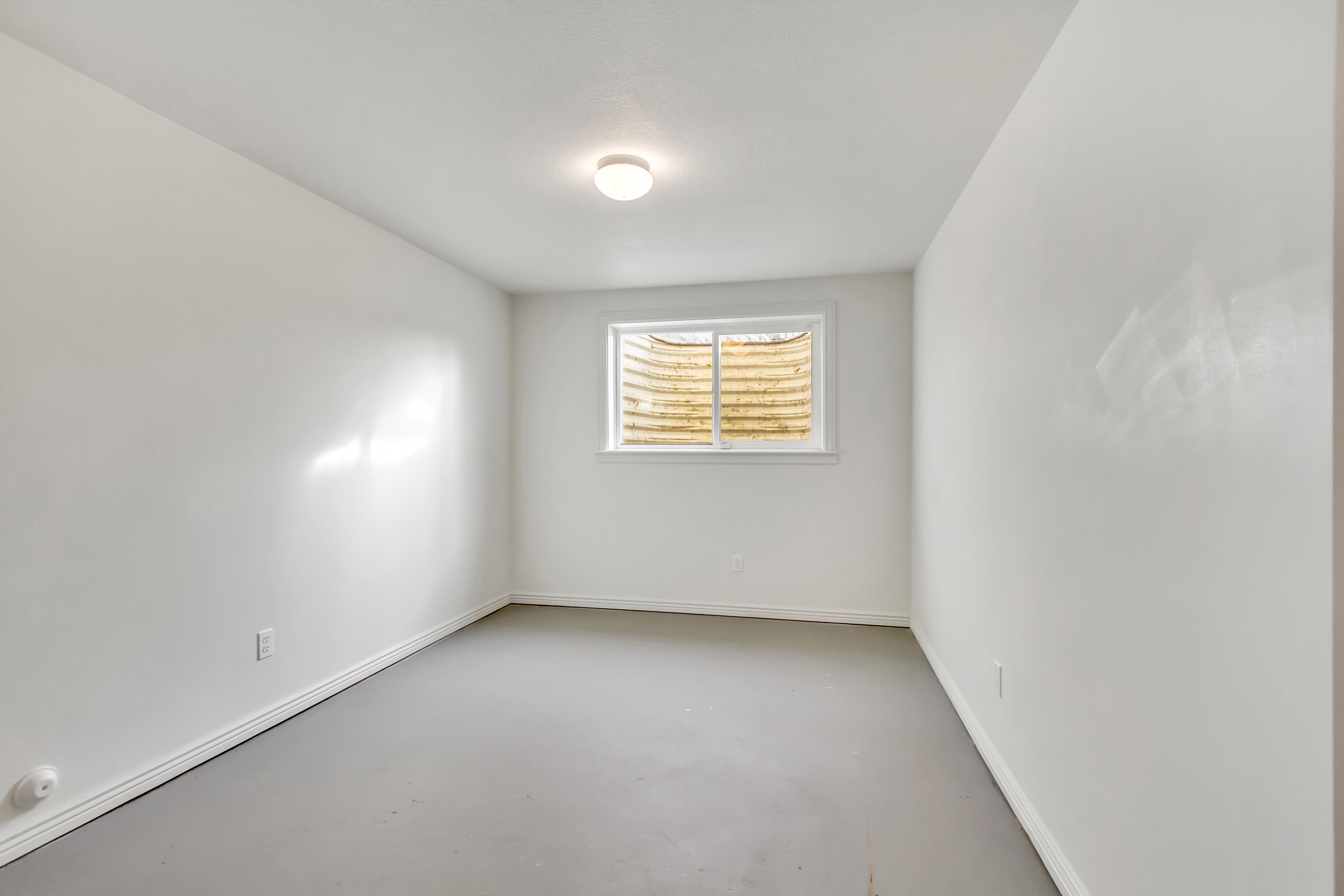 Neutral wall paint, white trim, and a window with an exterior window well