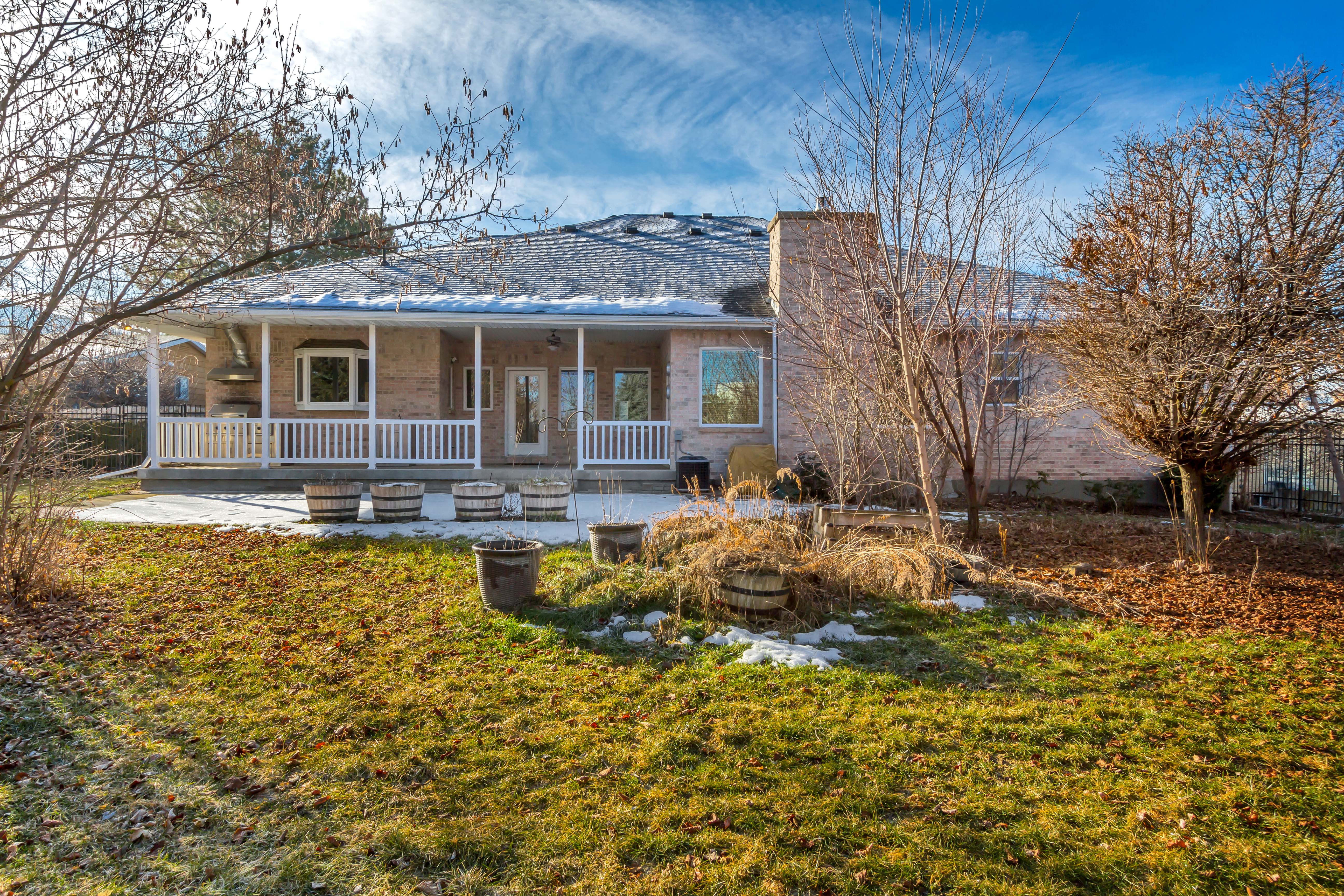 Rear exterior featuring a covered patio with white railings, a bay window, and a brick facade
