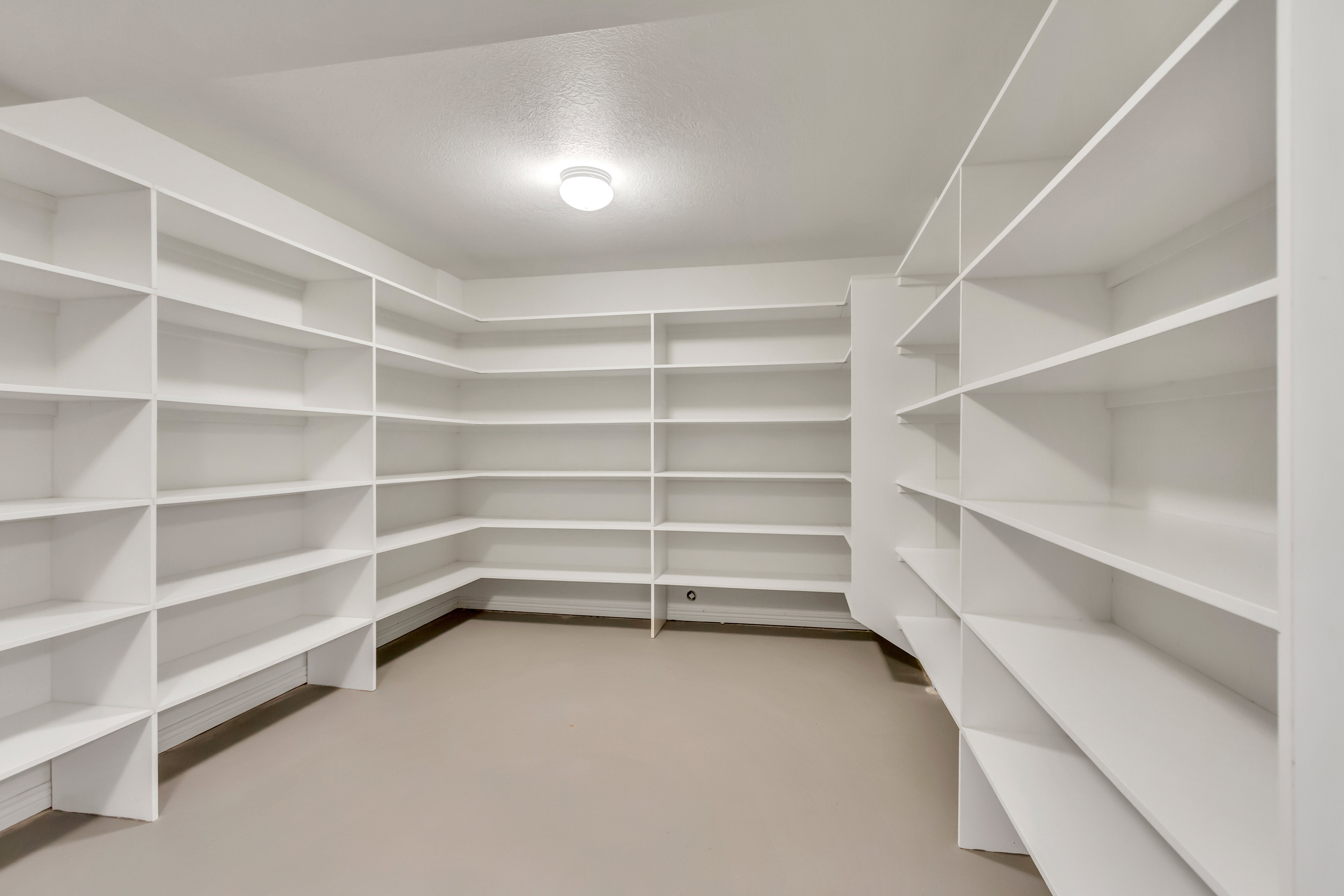 Spacious utility room featuring extensive built-in shelving, durable flooring, bright overhead lighting, and white walls